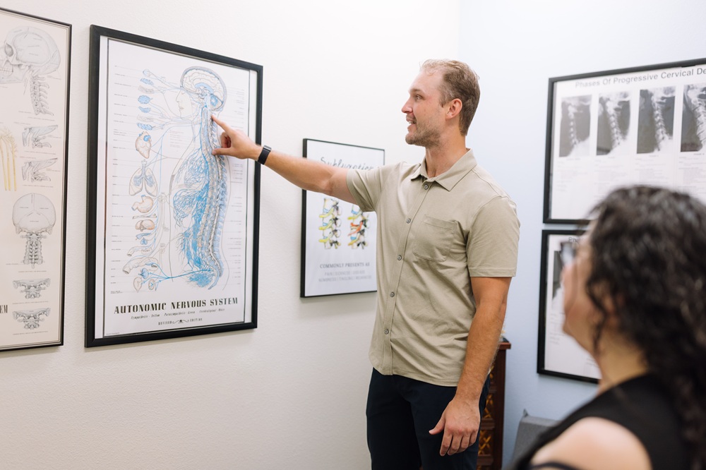 Discussing spine and nervous system anatomy during a chiropractic consultation in San Diego, CA Chiropractor explaining the autonomic nervous system to a patient using a wall chart in Mission Valley, San Diego, CA