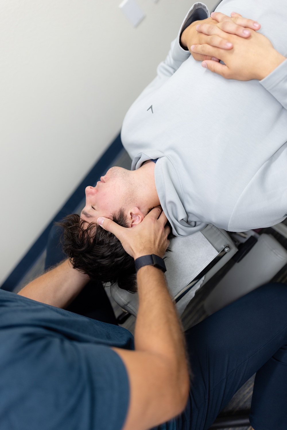 Cervical adjustment technique for headache relief in San Diego, CA Chiropractor cradling a patient's head and neck during a treatment session