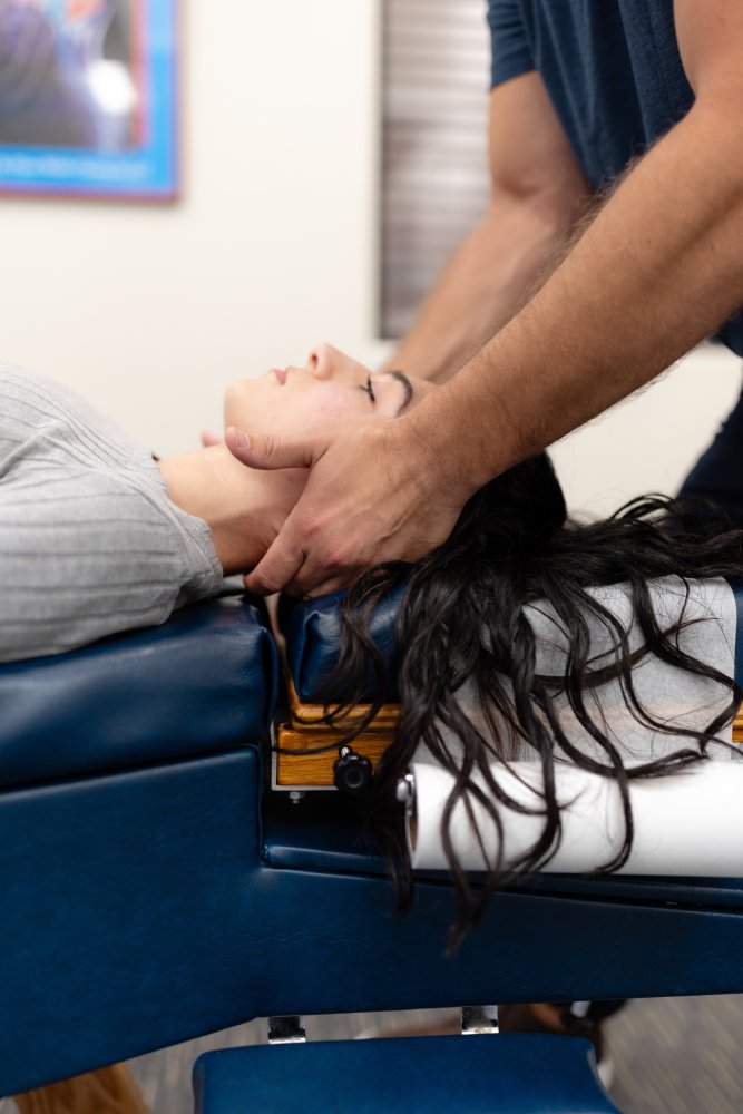 Cervical adjustment for neck pain relief Chiropractor performing a gentle neck adjustment on a patient lying on a treatment table